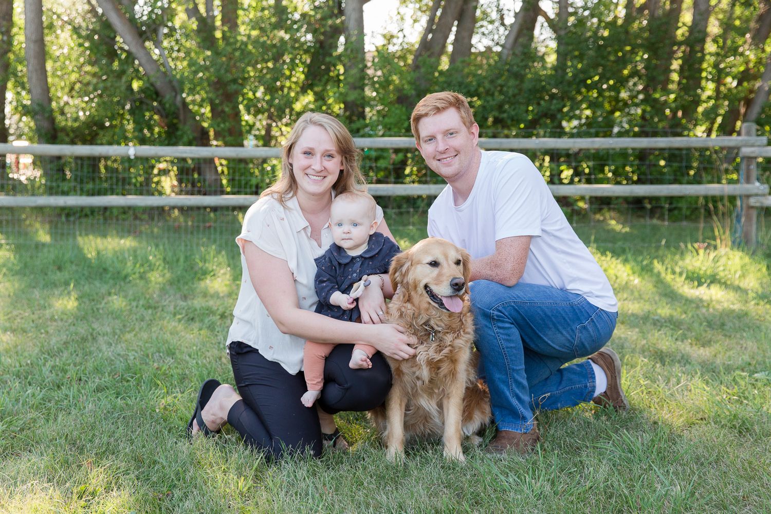 Family portrait with golden retriever dog in sunny backyard setting.