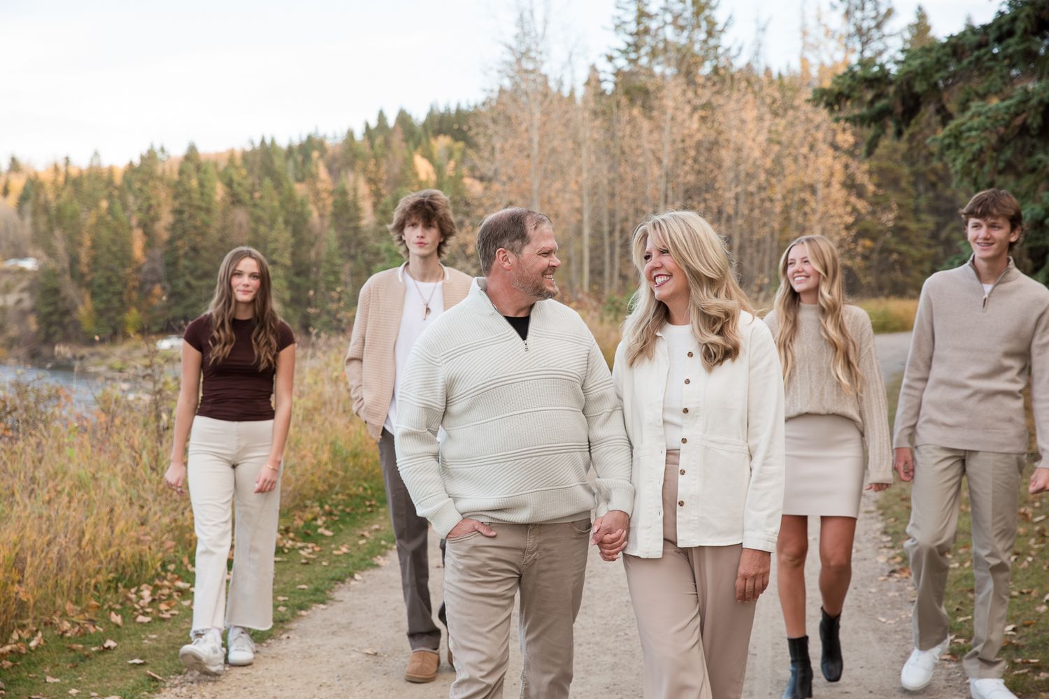 Group walks together on autumn trail wearing coordinated cream and beige outfits.