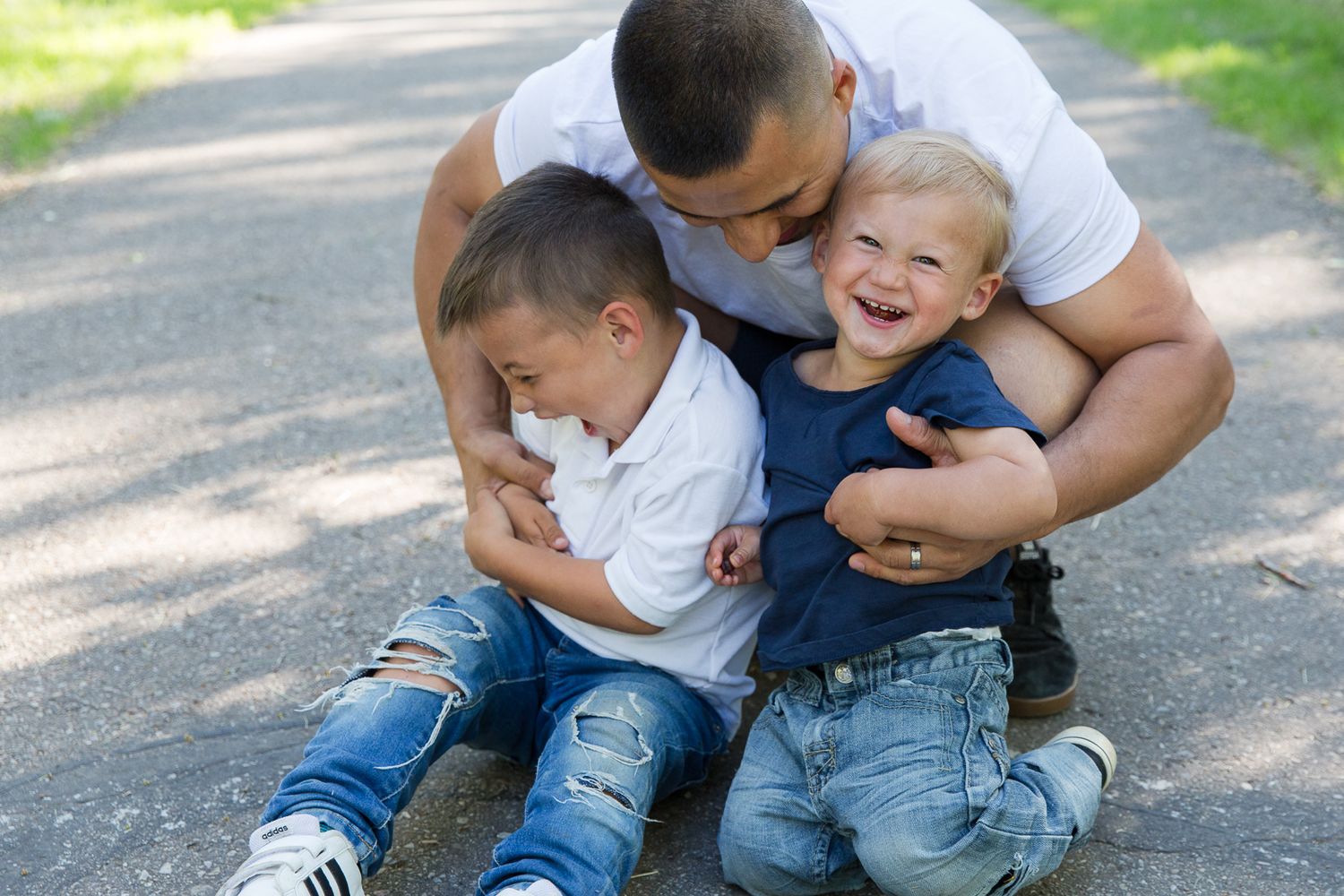 Three people share playful moment together on a sunny path.