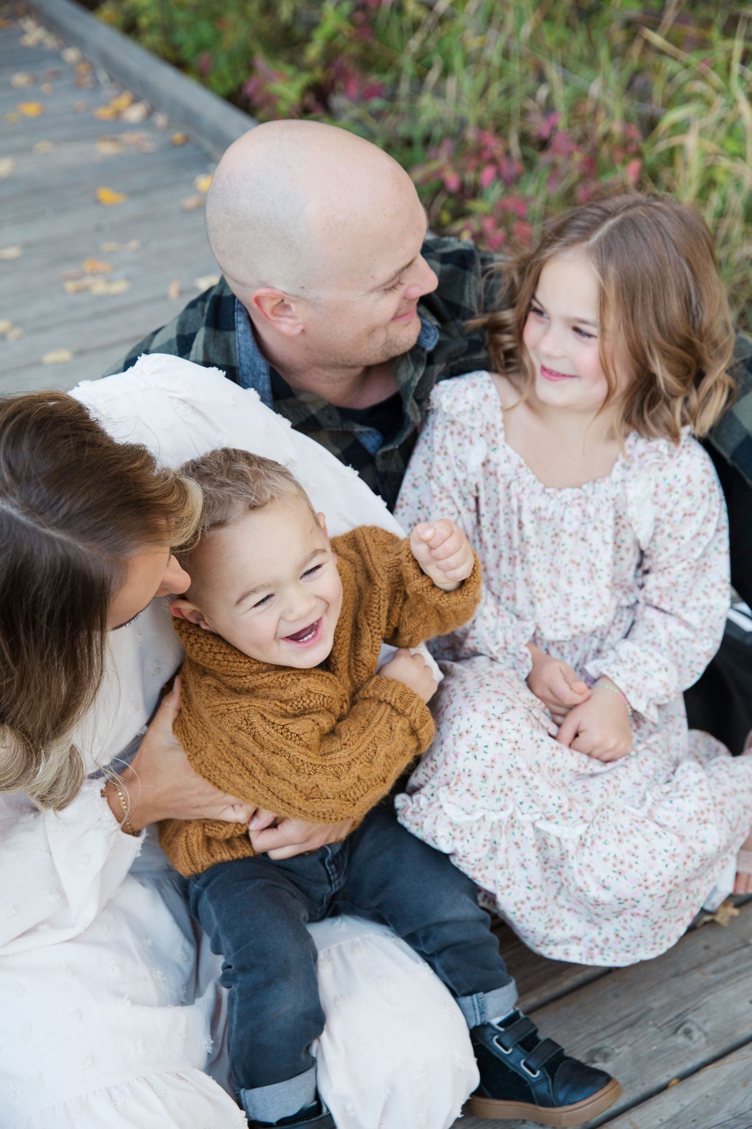 Family sharing tender moment on wooden deck surrounded by autumn foliage.