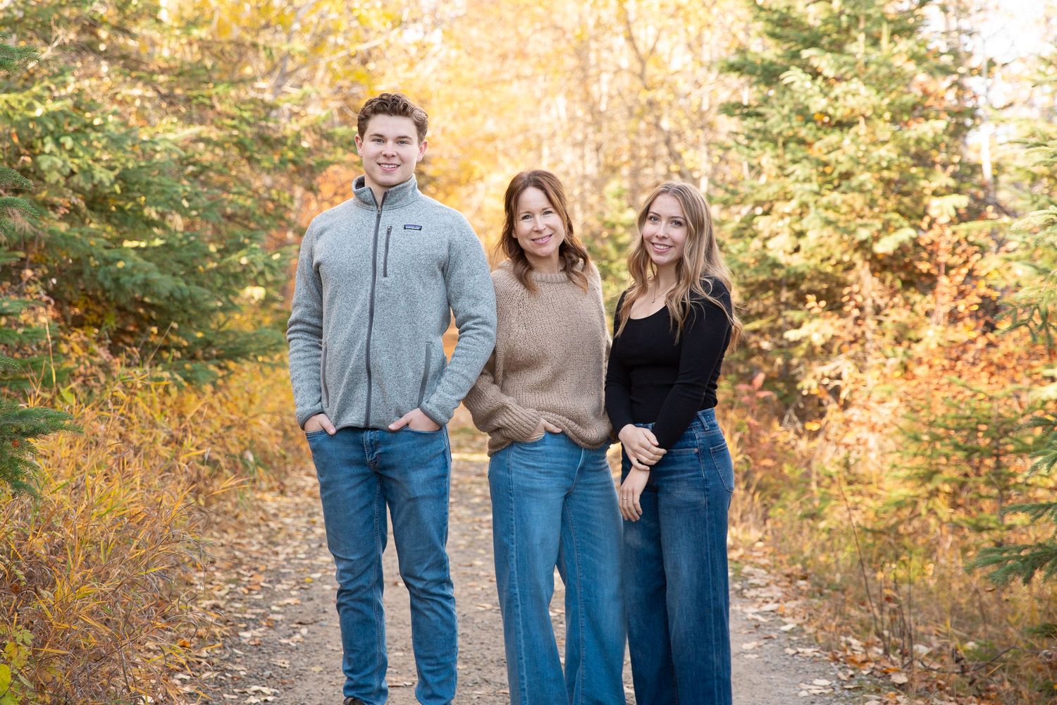 Family in casual wear walking together on autumn trail with golden foliage.