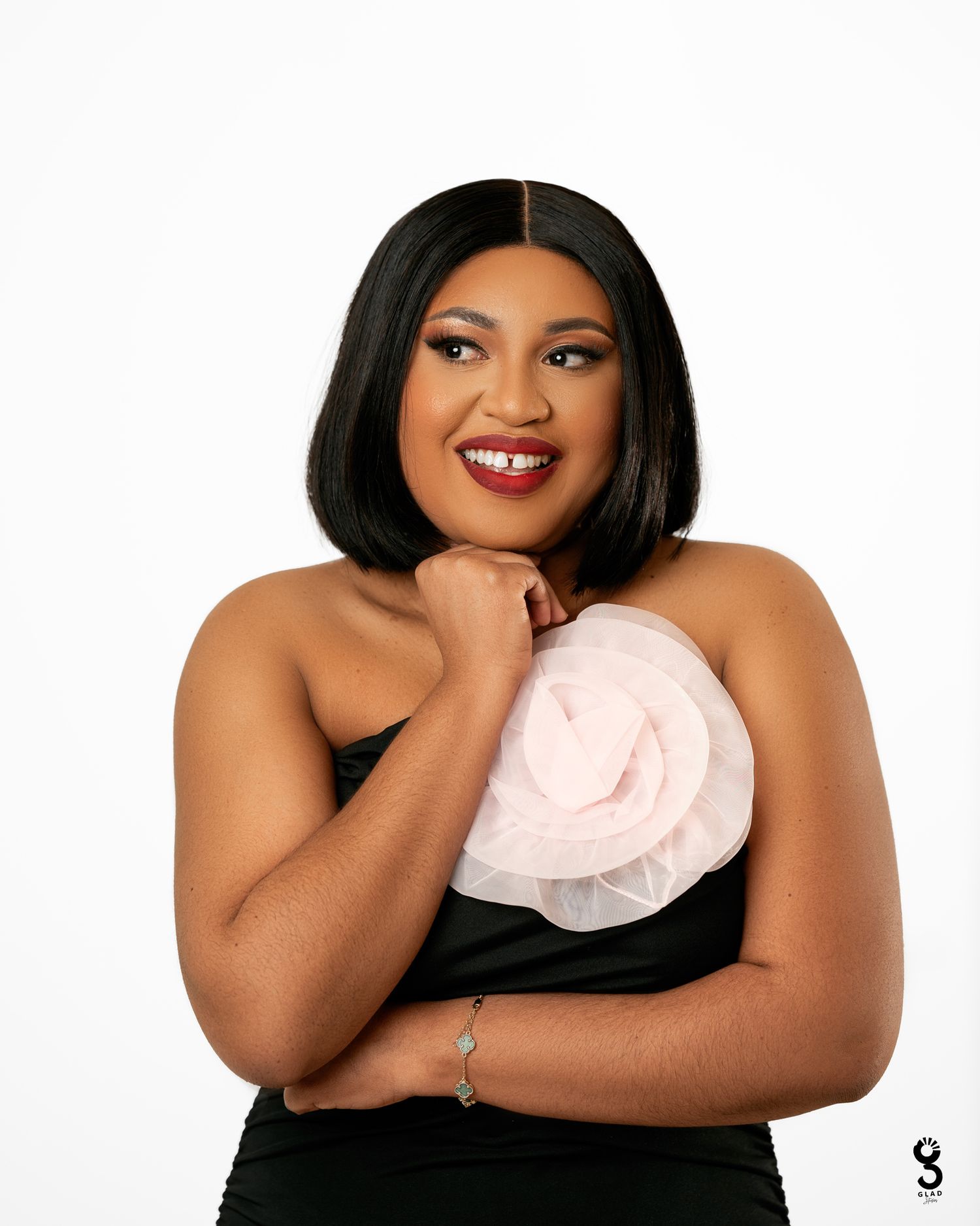 Studio portrait in black dress with white flower detail against white background.