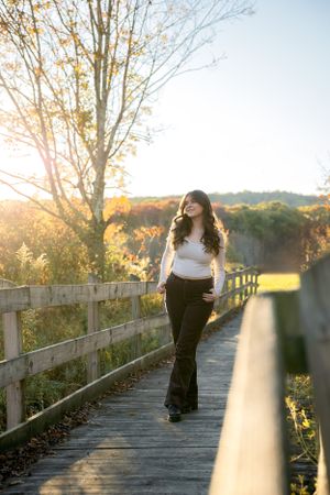client walks along wooden boardwalk surrounded by autumn foliage and golden sunlight.