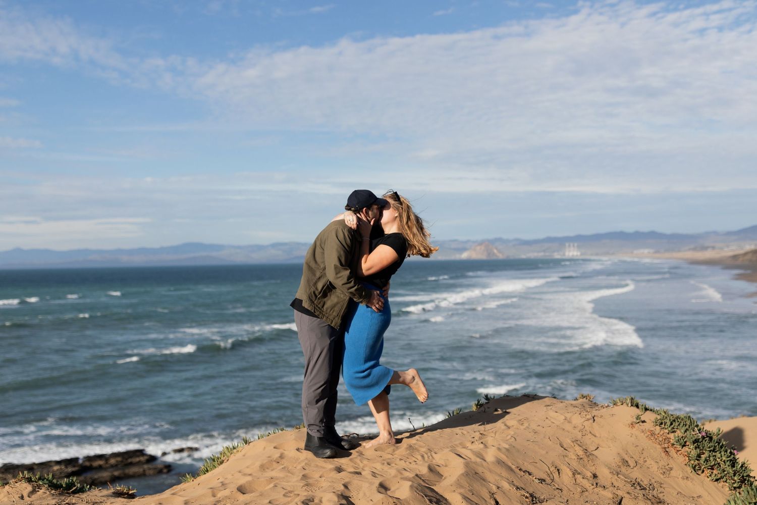 Scenic coastal engagement photoshoot with dramatic cliffs and ocean waves in background.