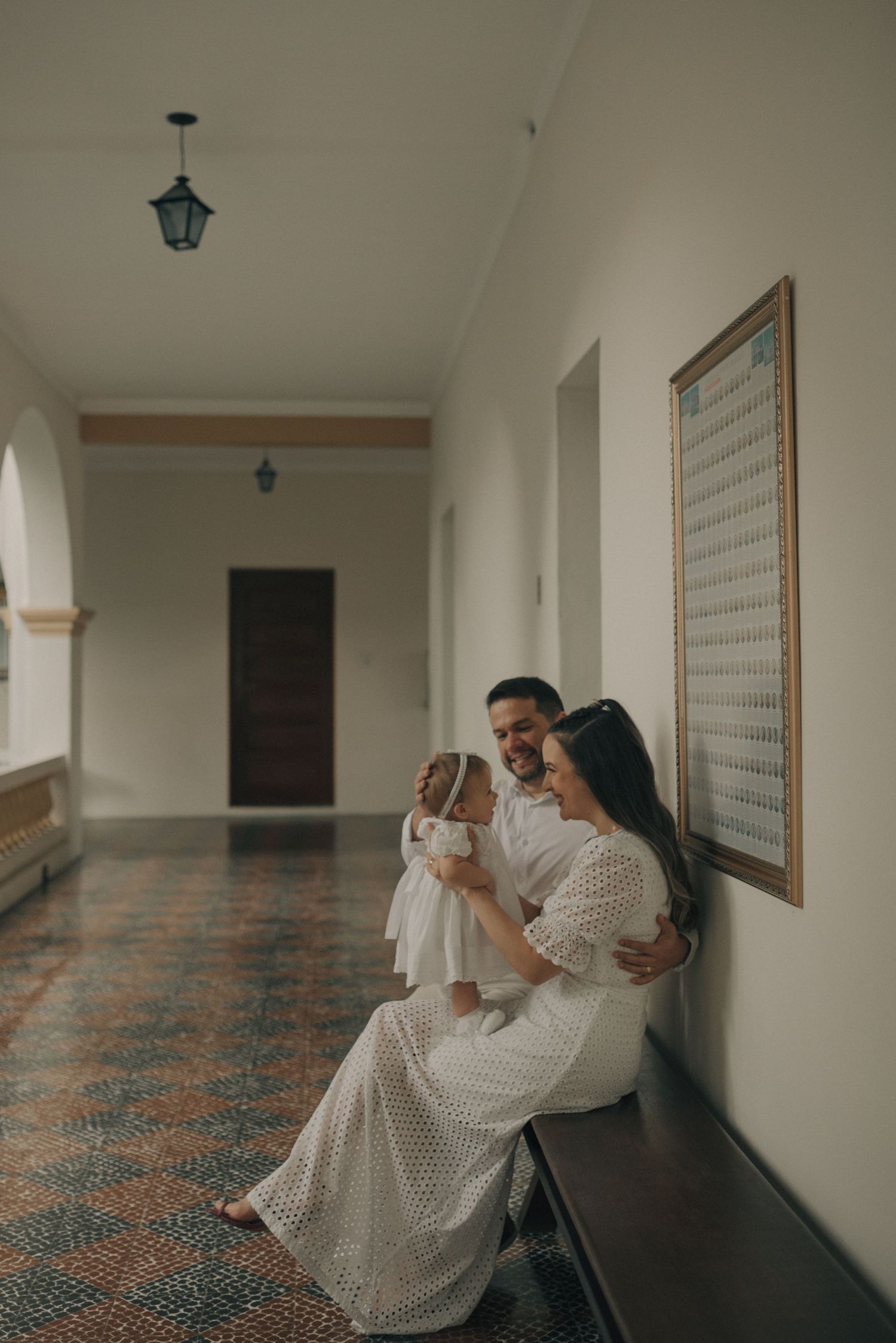 A tender moment captured in a church hallway with patterned floors and vintage lighting.