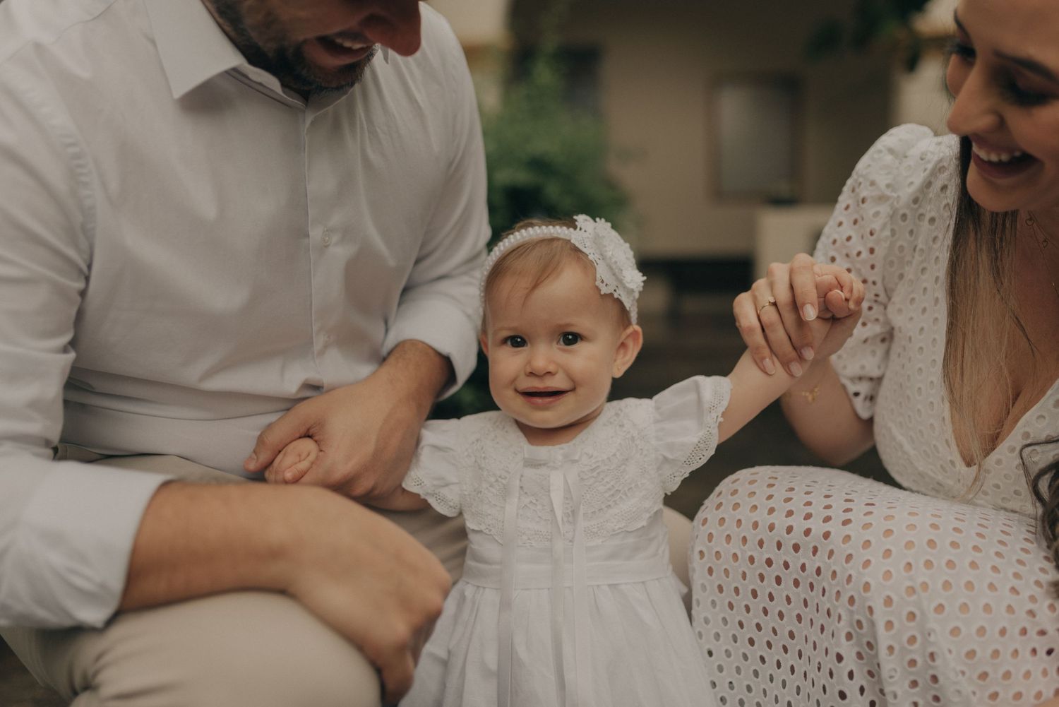 A joyful moment captured outdoors with a baby in a white dress.