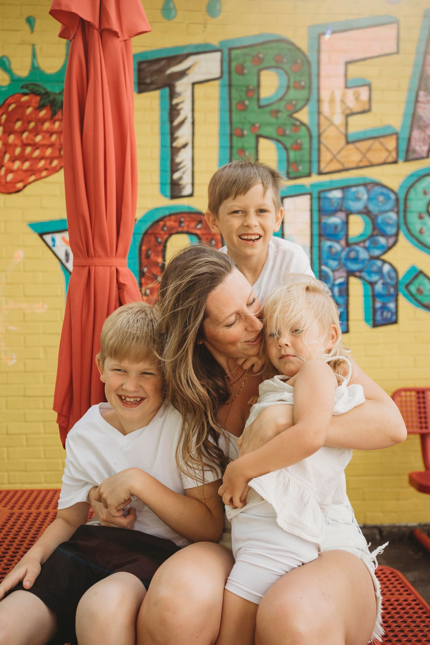 A joyful family moment captured against a vibrant yellow wall with colorful text and artwork.