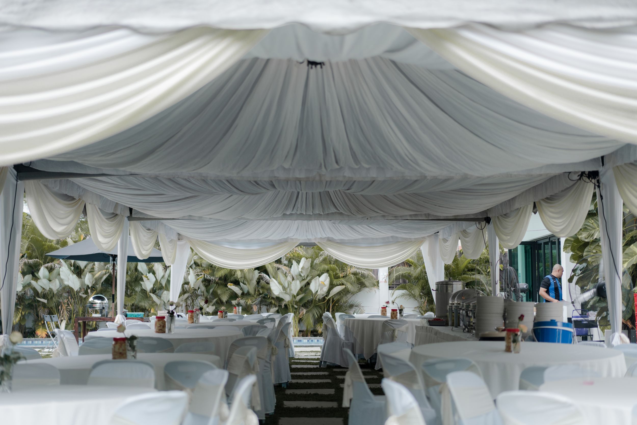 White draped fabric tent setup for an elegant outdoor event with chairs and tables.