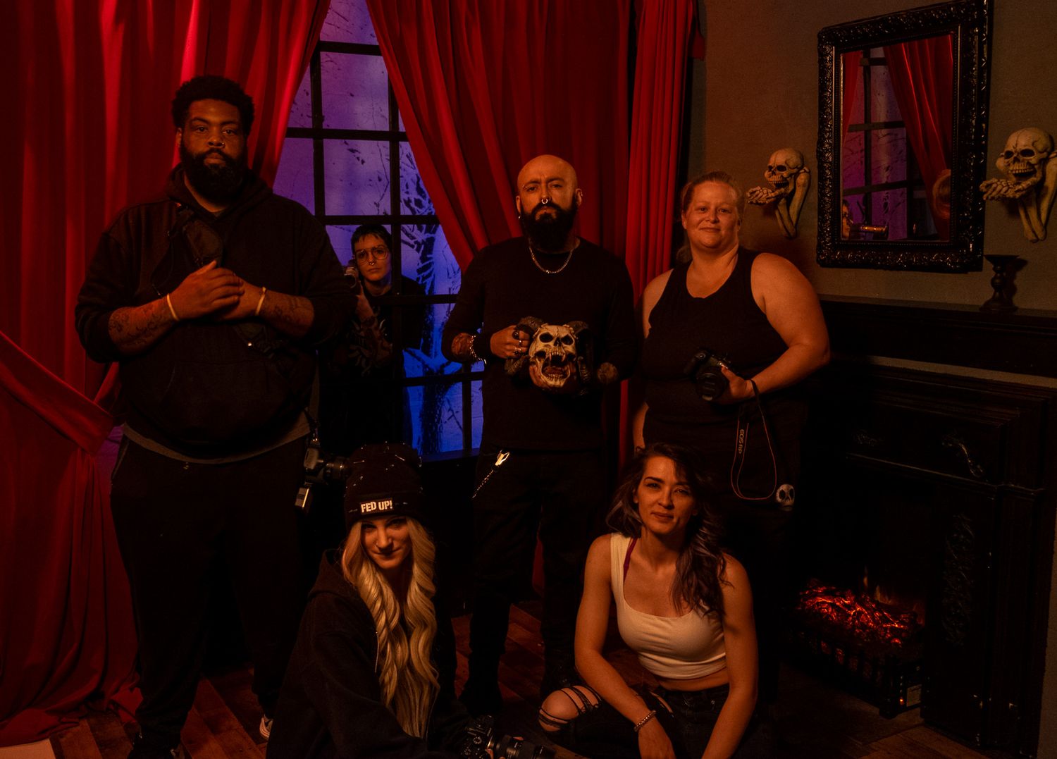 A small group of musicians pose together in front of audio equipment at what appears to be a music venue.