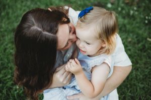 An intimate mother-child moment captured on grass during springtime.