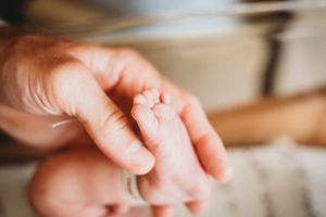 Close-up macro shot of a tiny baby's foot being held by an adult hand.