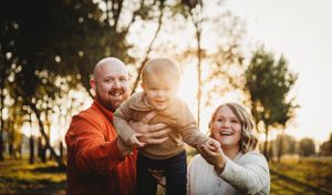A joyful family moment captured during golden hour in a park setting.