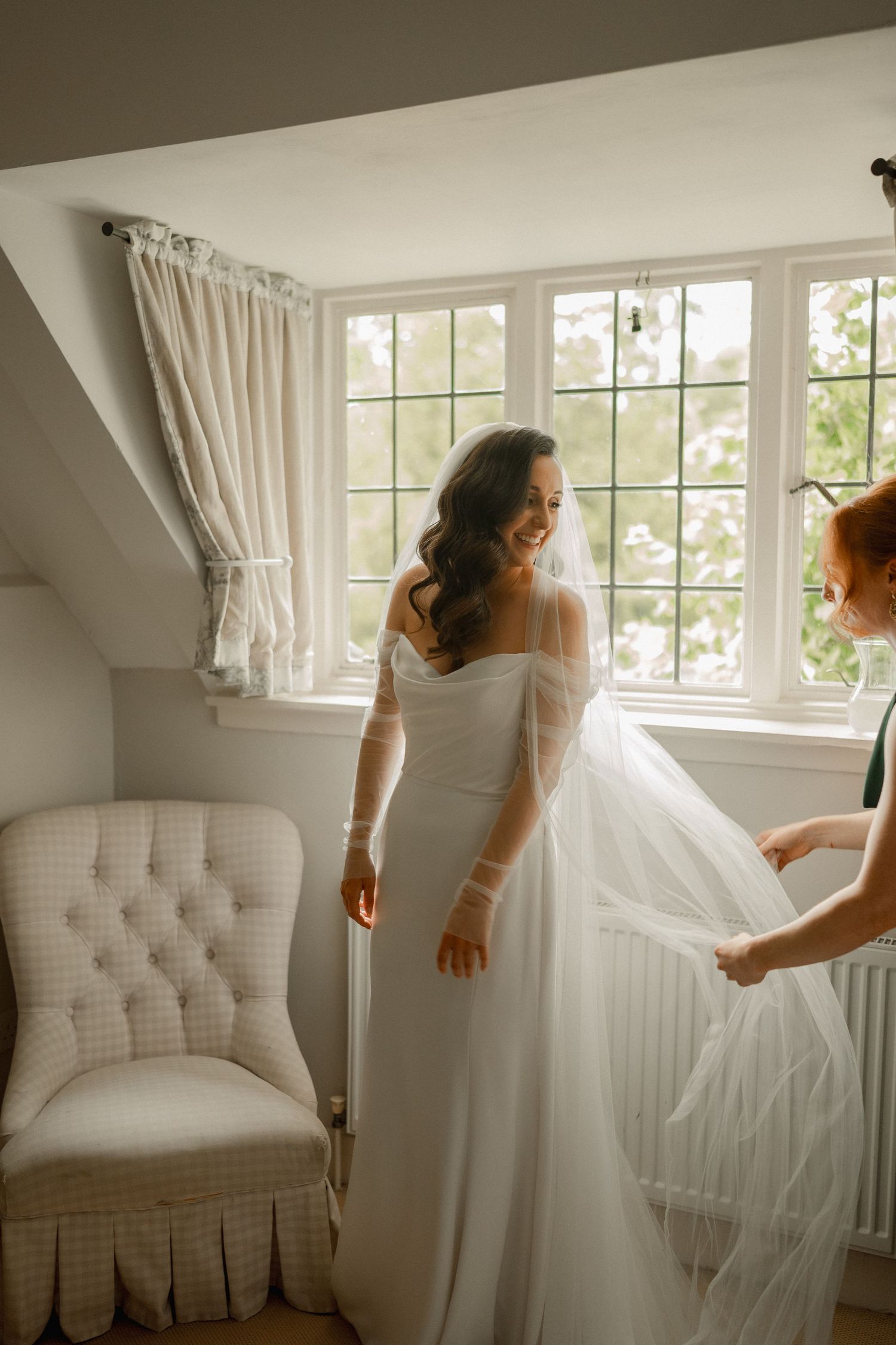 Bride and groom walking hand in hand toward a white gazebo in a sunlit garden on their wedding day.