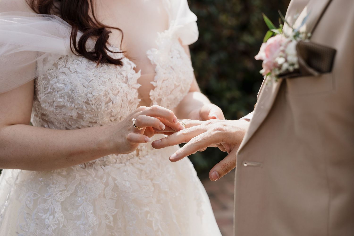Close-up details of delicate lace and beading on a white wedding dress bodice.