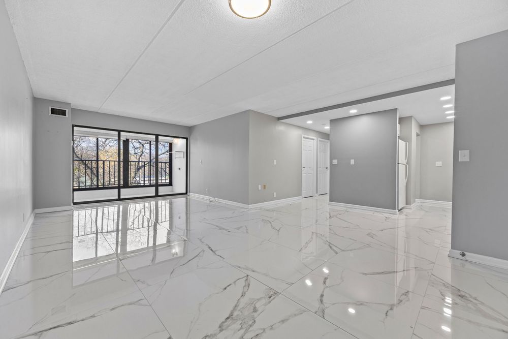 Bright open living area featuring polished marble floors and large windows with gray walls.
