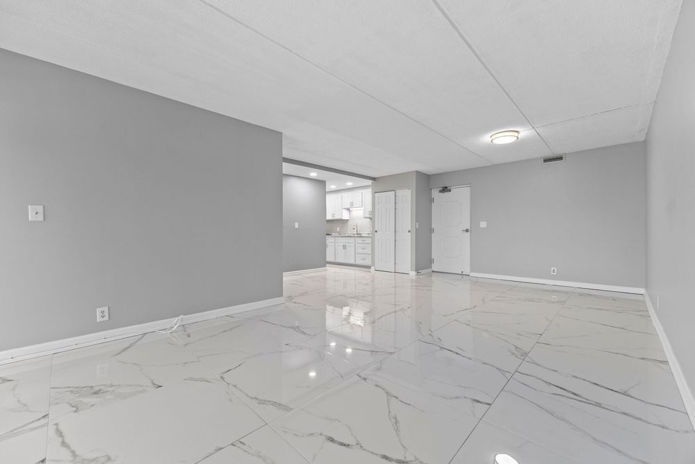 Modern empty room with gleaming white marble tile floors and neutral gray painted walls.