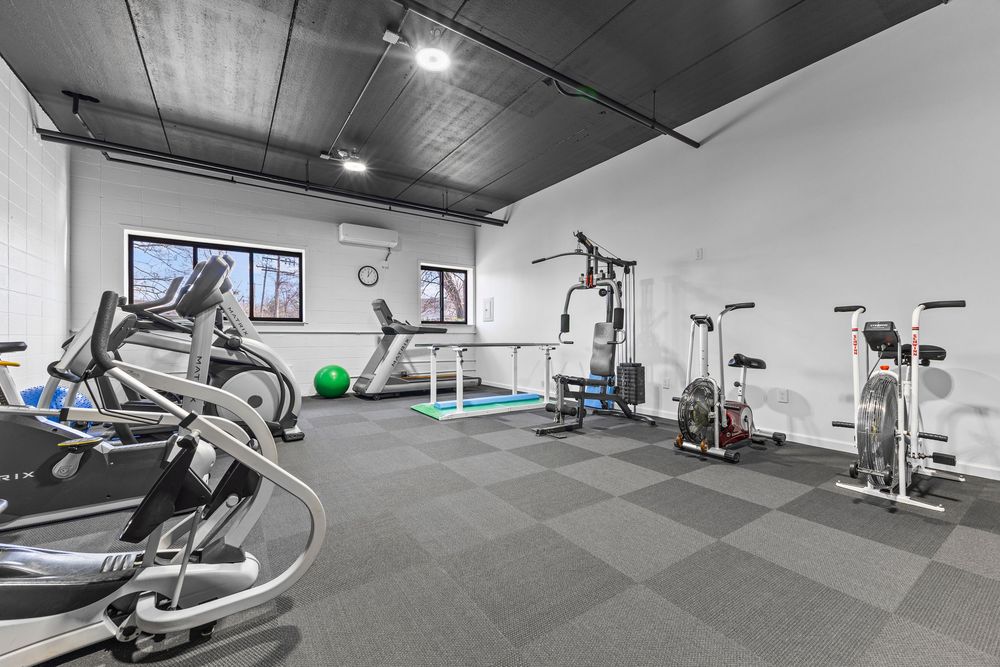 Well-equipped fitness center with cardio machines, weight equipment, and rubber flooring.