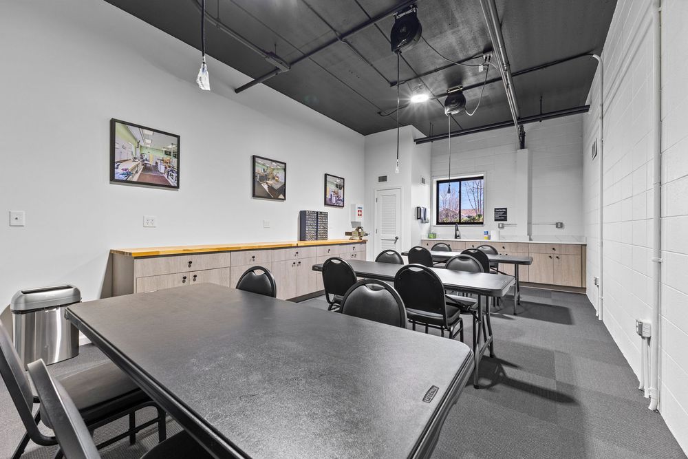 Multi-purpose community room with dark countertops, folding chairs, and track lighting.