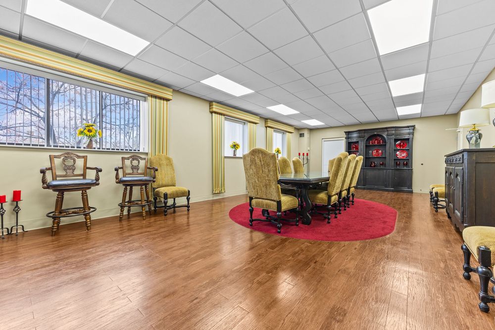 Spacious dining room with hardwood floors, elegant furniture, and a red area rug at Morley Manor.