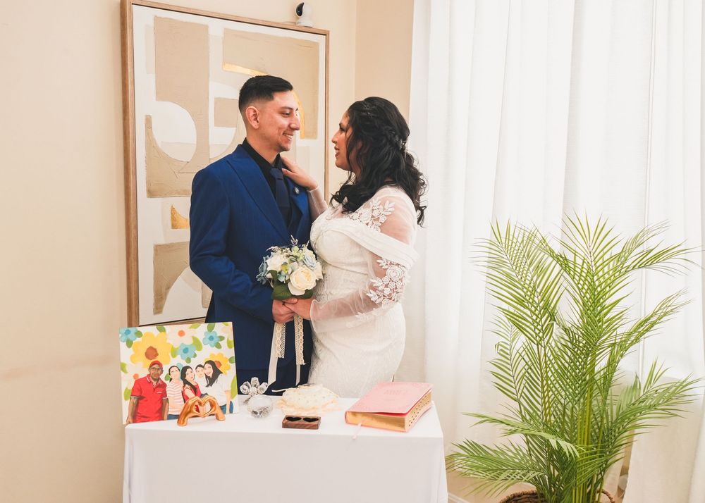 Couple sharing a tender moment at wedding ceremony table with bouquet and decor.