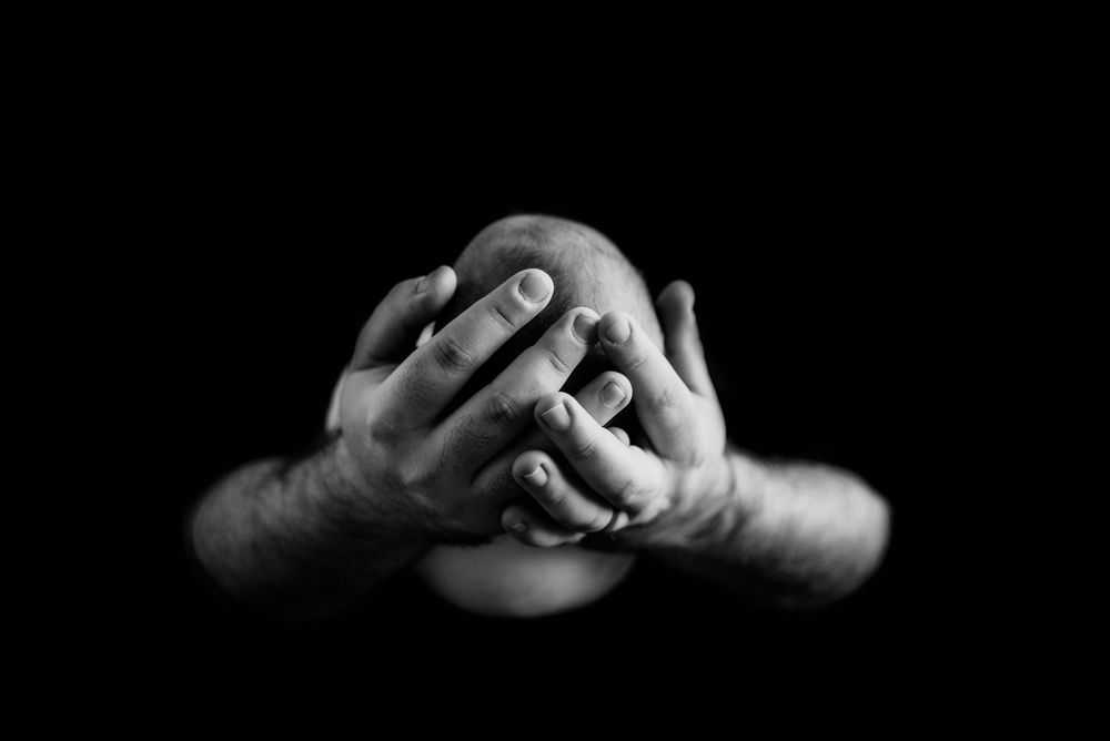black and white image of a newborn in dads hands