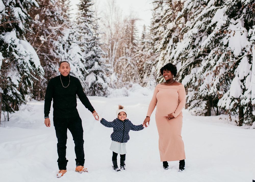 Family walking together through a snowy winter forest during an outdoor family photography session