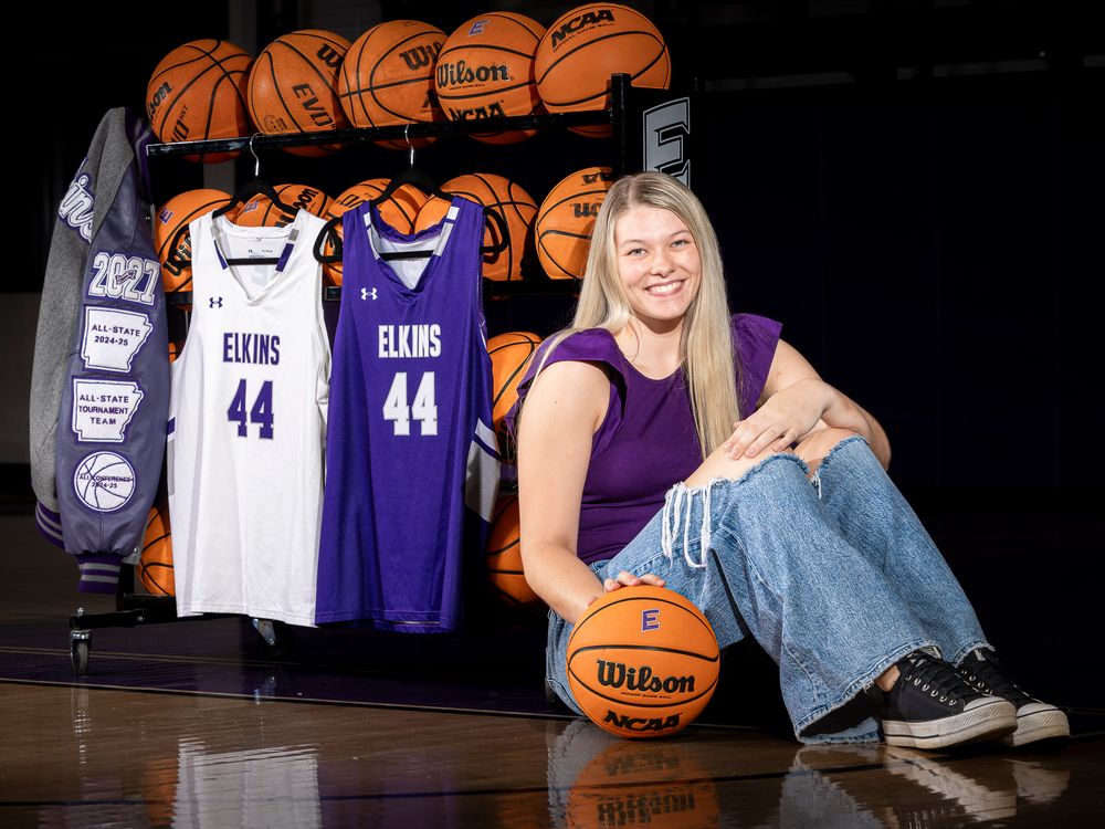 Female athlete poses on basketball court beside Elkins #44 jerseys and Wilson basketballs in purple and white.