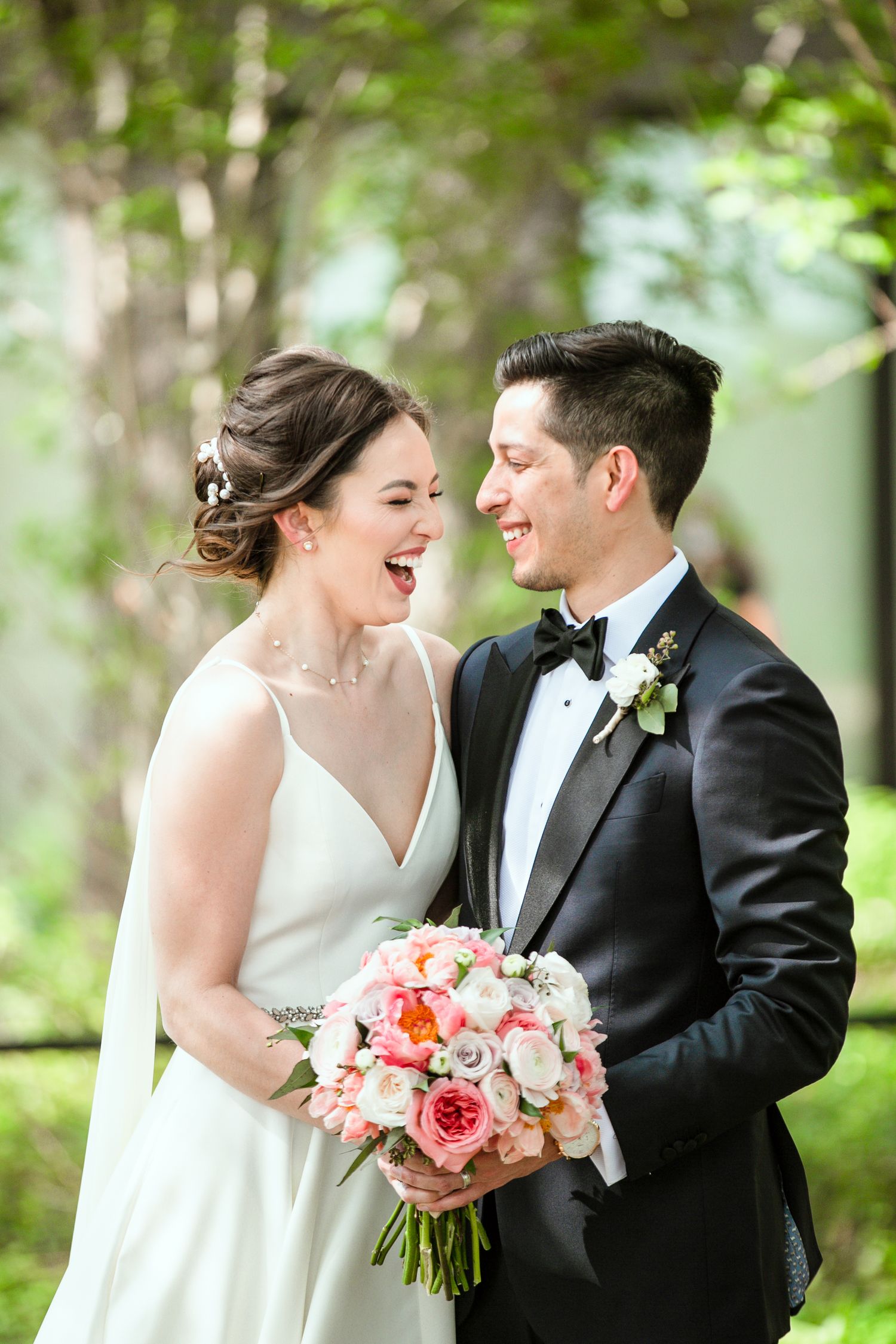 Candid photo of a bride and groom holding each other and laughing before the ceremony at the Botanical Garden in San Antonio Texas.