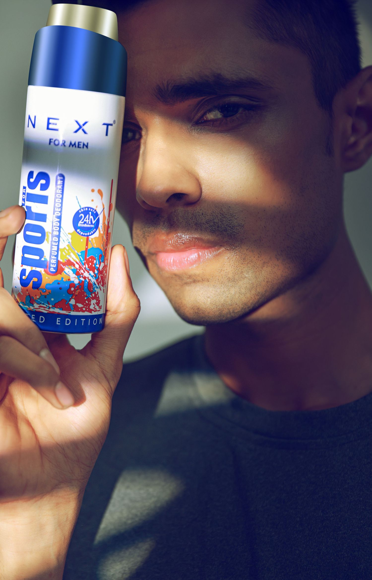 Man holding Next For Men Sports Limited Edition 24H body spray deodorant close to his face.