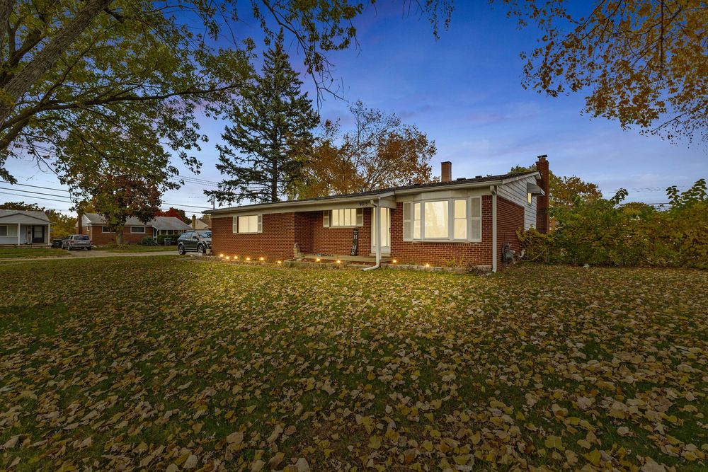 Brick ranch home with attached garage and large yard filled with colorful autumn foliage.