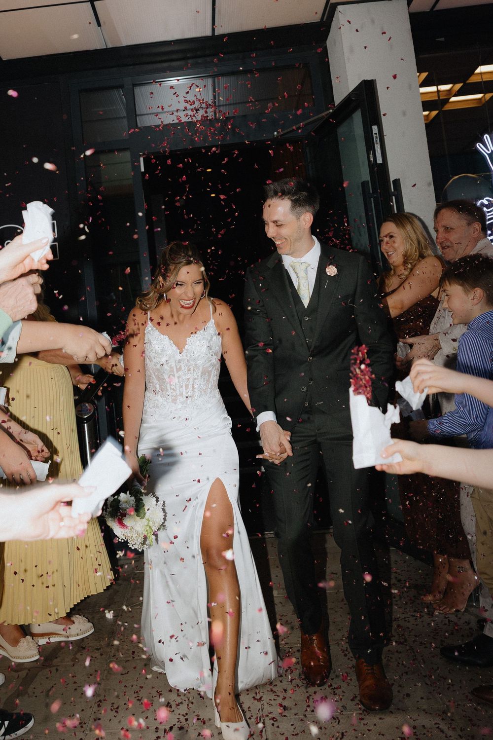 Bride and groom entering the venue surprised with confetti by their guests at a wedding reception in Manchester