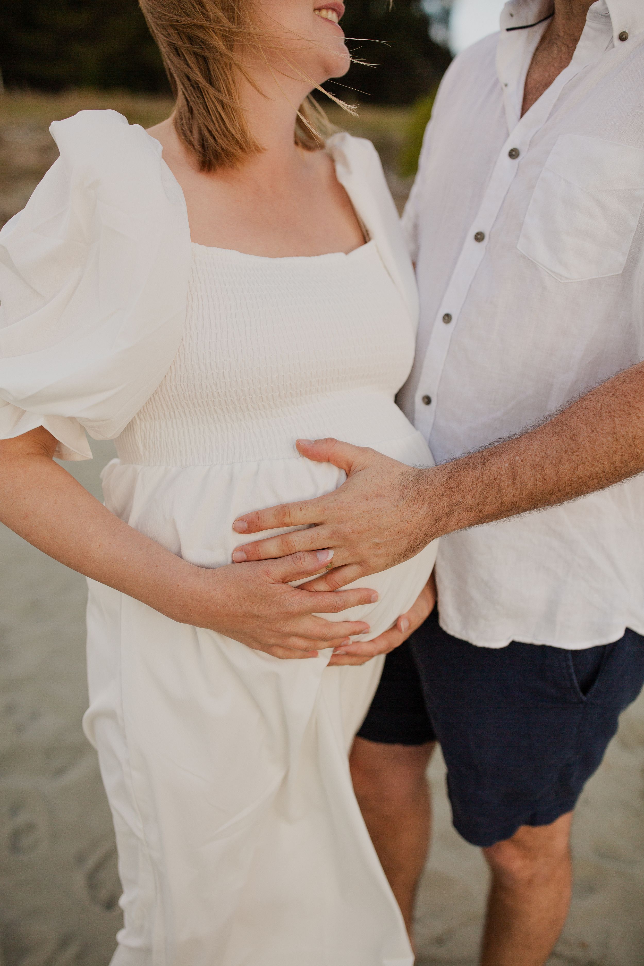 Family photo session on the beach. Maternity, family portrait at rabbit island. Overcast, windy beach afternoon. 
Mum and dad and bump crop.
