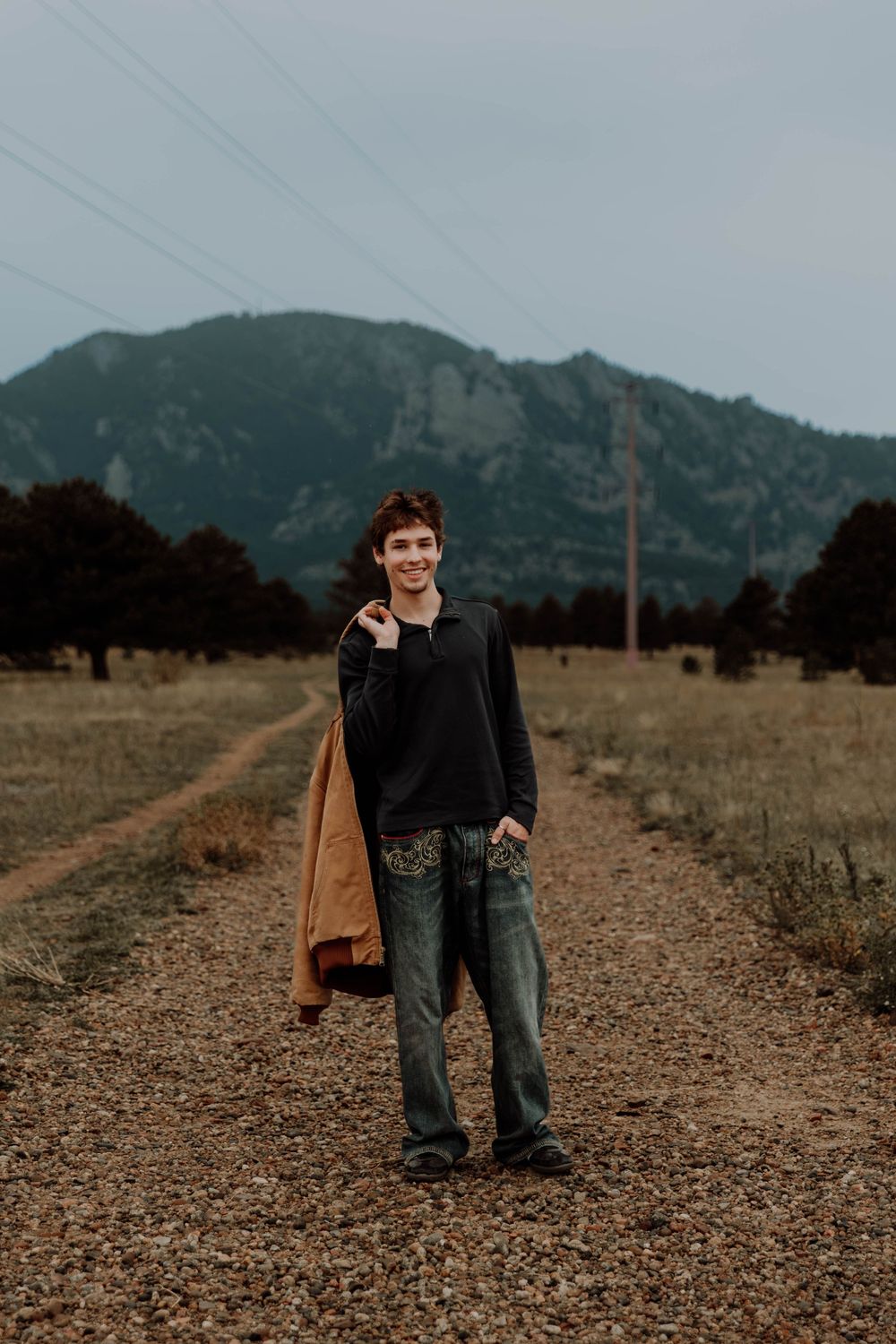 Boy stands, smiles, and poses for senior photos, cinematic, mountain, and portrait photos in Boulder, Colorado outside and in nature