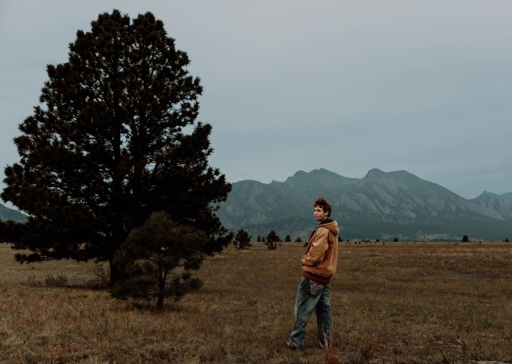 Boy stands, and poses for senior photos, cinematic, mountain, and portrait photos in Boulder, Colorado outside and in nature