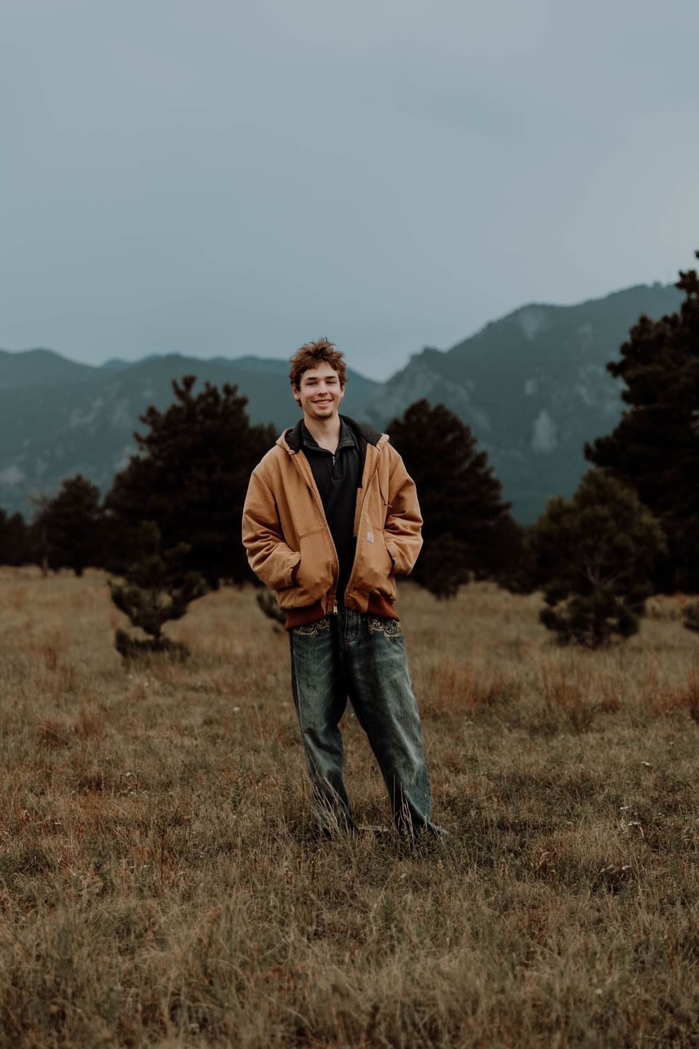 Boy stands, smiles, and poses for senior photos,cinematic, mountain, and portrait photos in Boulder, Colorado outside and in nature