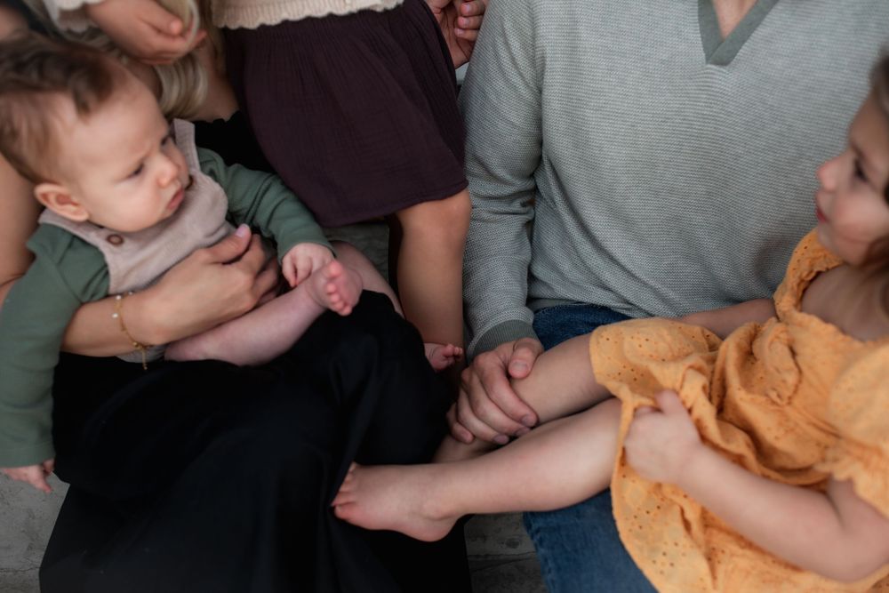 Adults sitting together holding babies and toddlers, capturing a warm family gathering moment with young children.