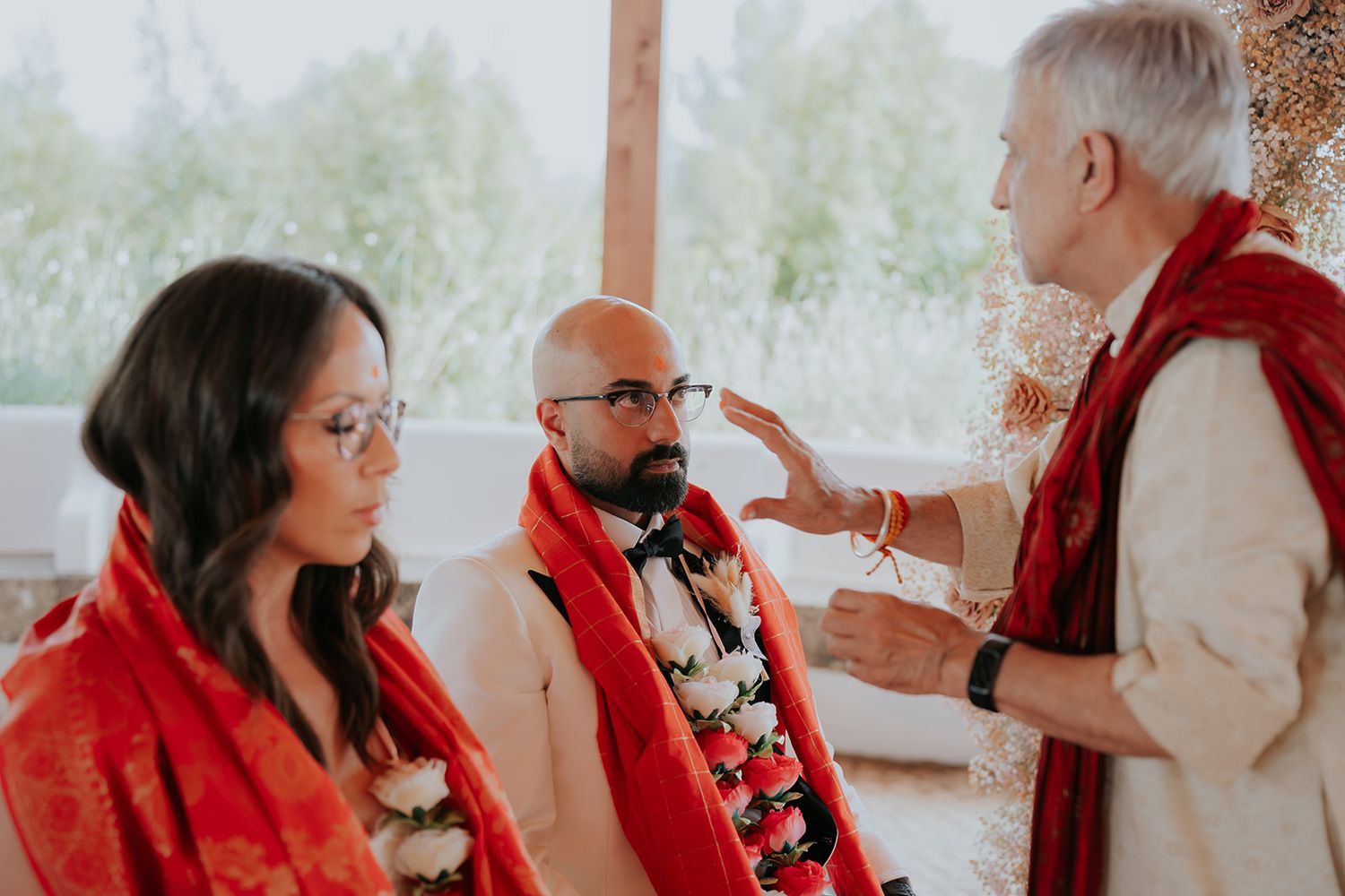 Traditional ceremony with guests in red and white attire in natural setting.