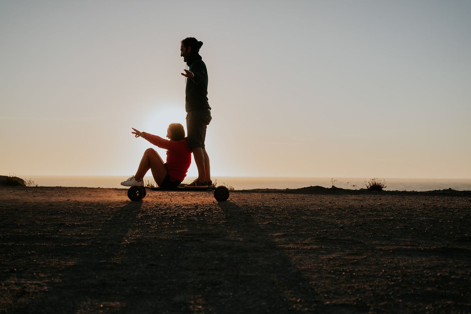 Silhouettes against sunset sky during outdoor wedding photography session.