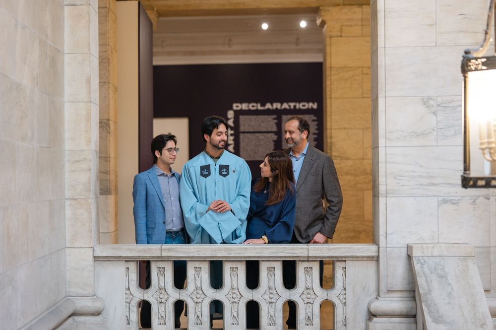 Group of four people smiling together at a graduation event near a Declaration exhibit.