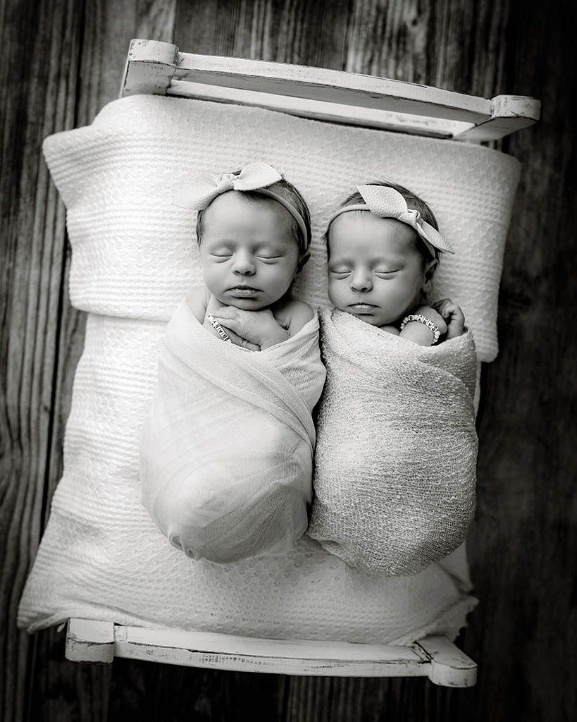 Black and white photo of twin newborn babies swaddled in white wraps by Murrieta newborn twins photographer.