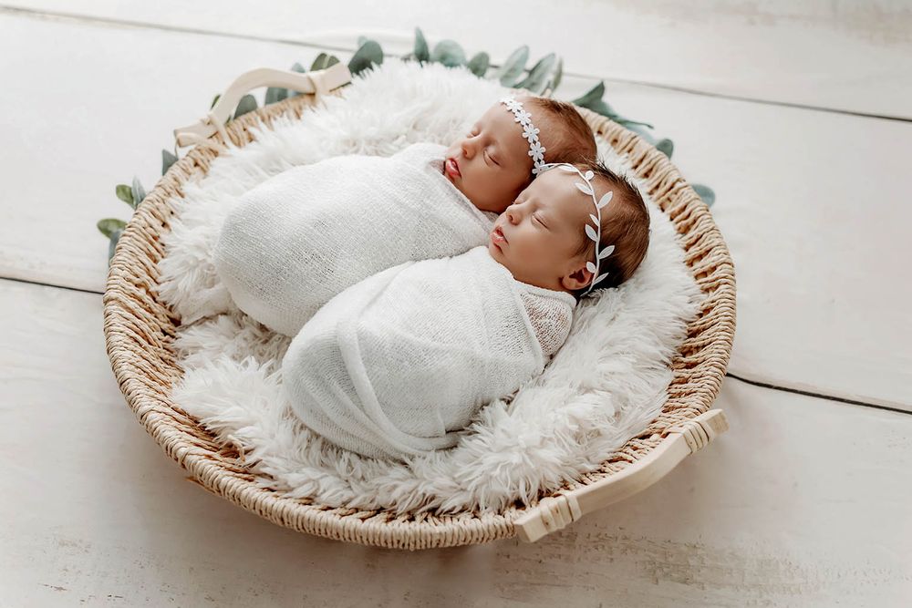 Twin newborns wrapped in white swaddles wearing floral headbands by Murrieta newborn twins photographer.