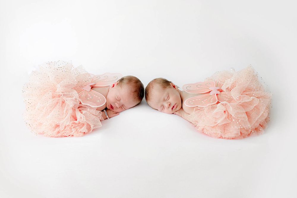 Two sleeping newborn twin girls in matching pink tutu skirts by Murrieta newborn twins photographer.