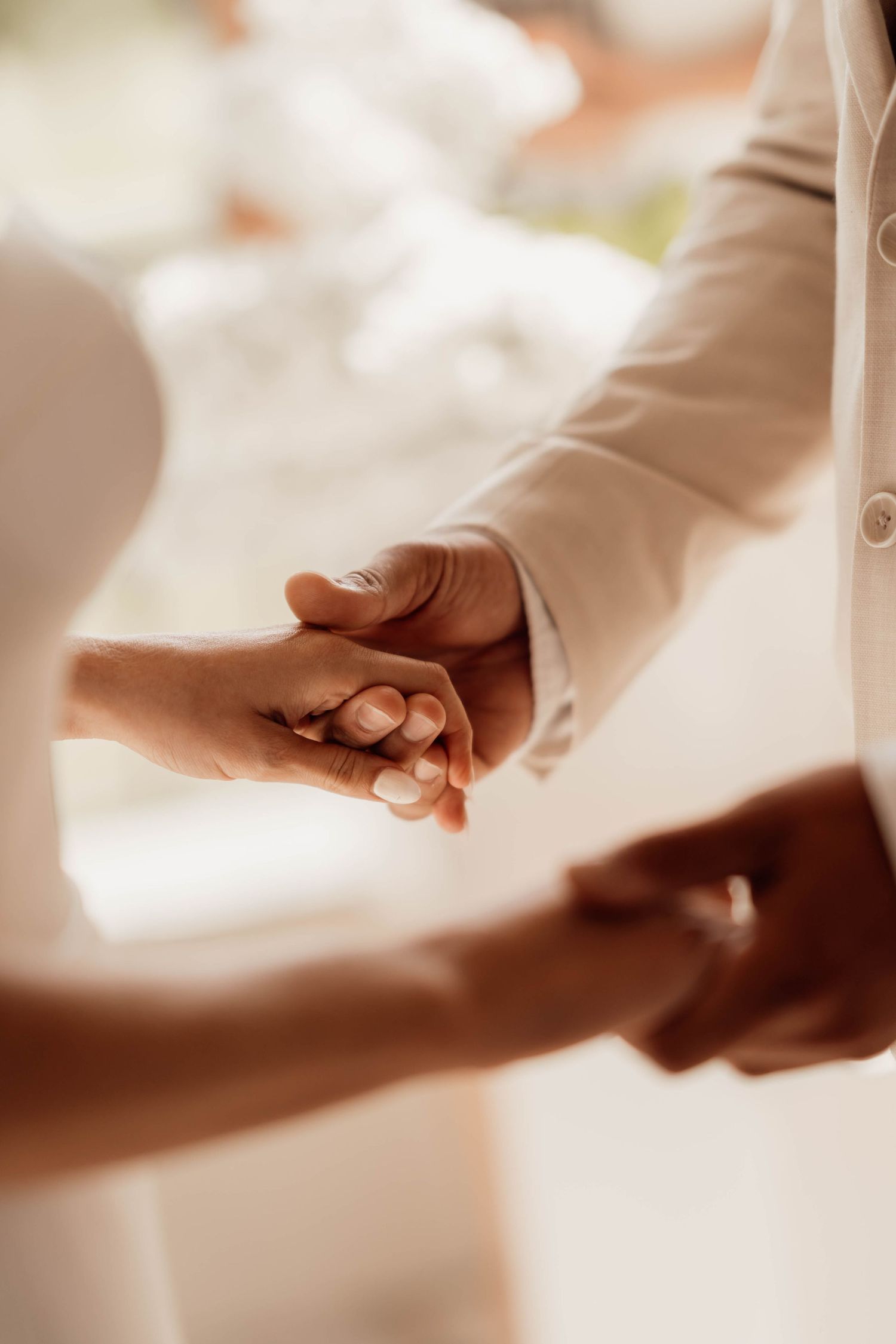 Close-up of a bride and groom holding hands tenderly on their wedding day.