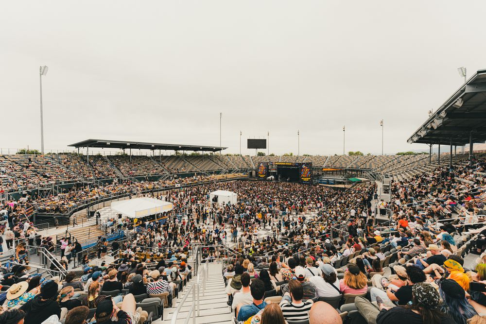 Large outdoor stadium packed with crowds watching a live event on an overcast day.