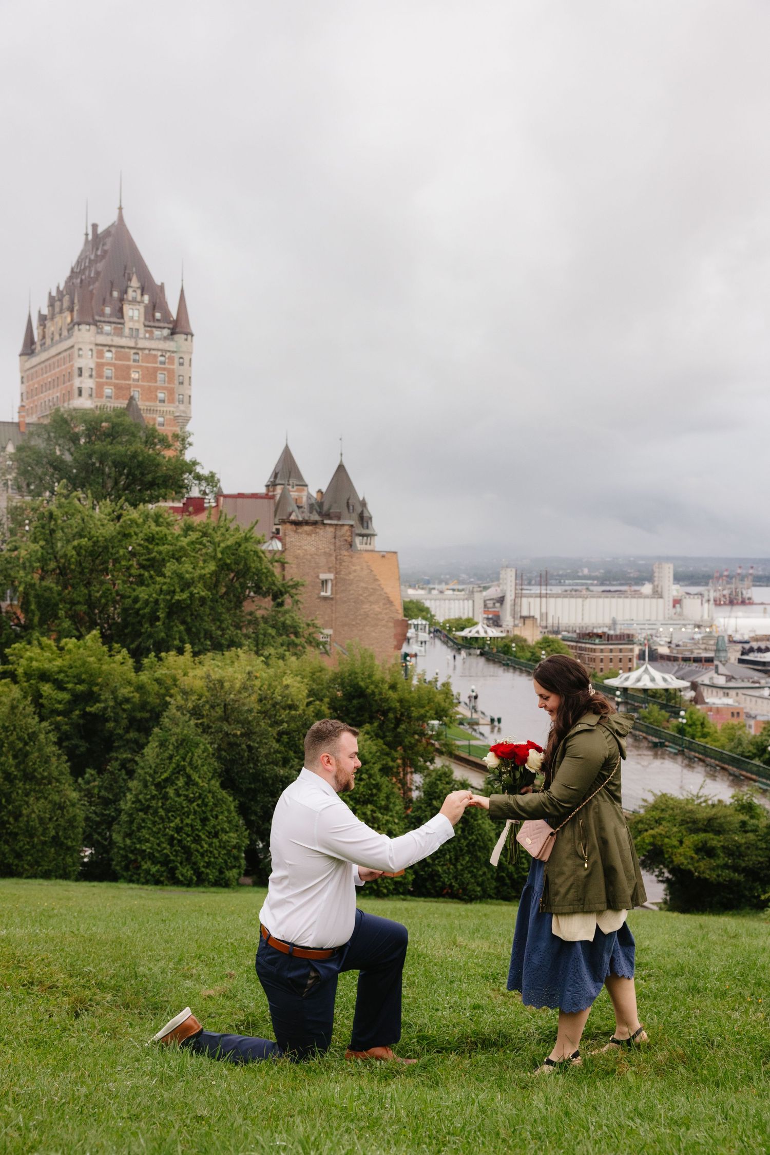 Marriage proposal scene in front of Chateau Frontenac in Quebec City with scenic river view.