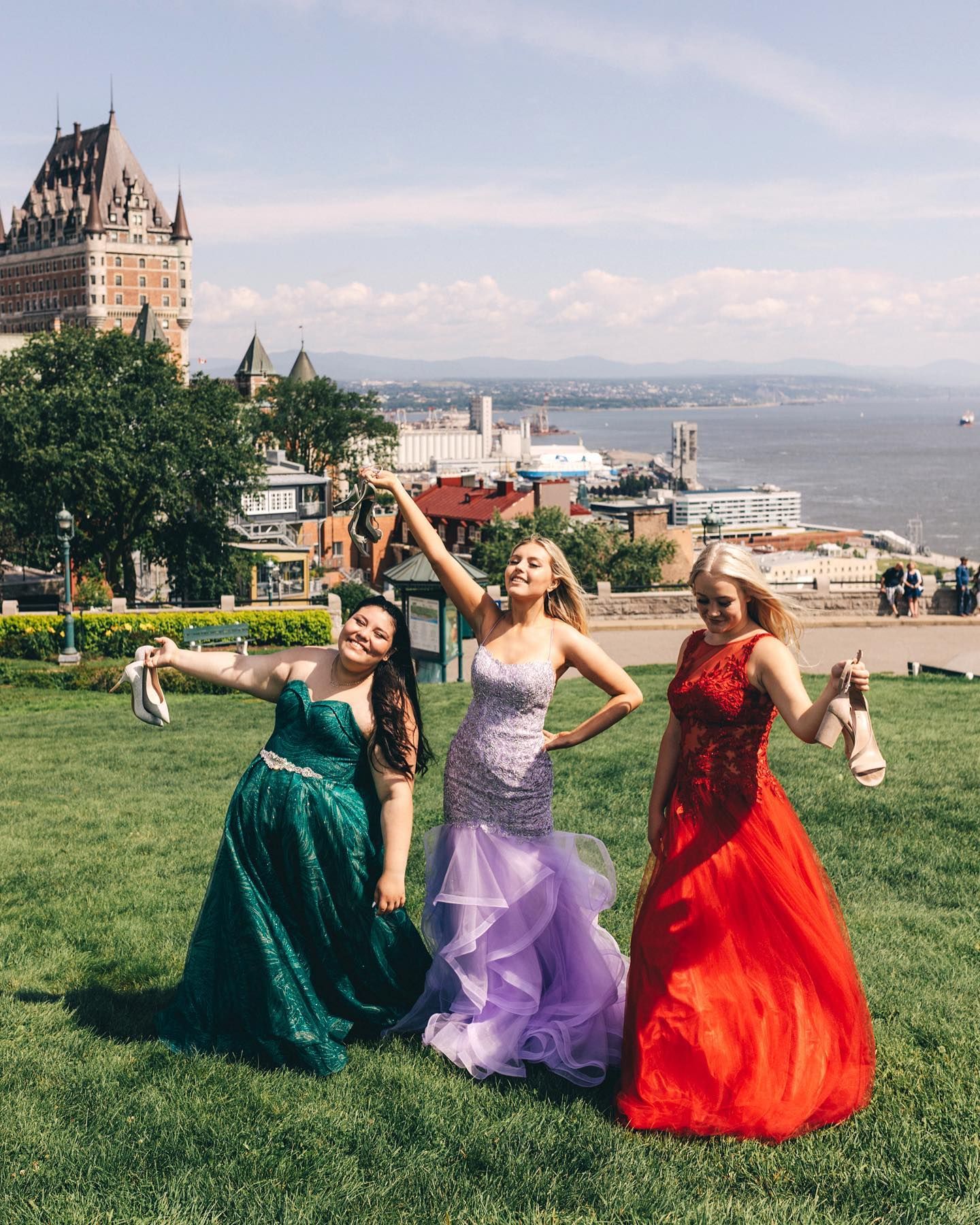 Three elegant dresses dancing on lawn with Chateau Frontenac and St Lawrence River in background.