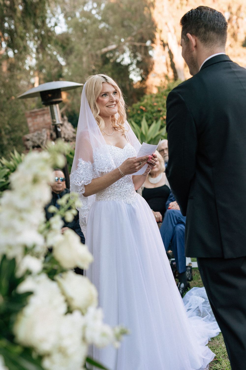 Candid portrait of a bride laughing during an outdoor wedding ceremony, with warm, golden hour backlighting.