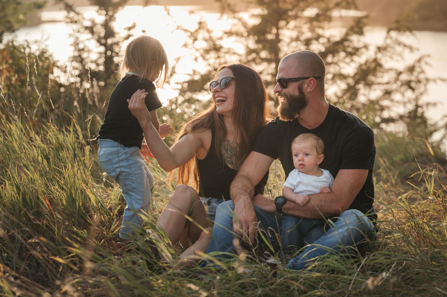 Warm outdoor family session with young kids, playful connection, green tones and soft filmy texture.