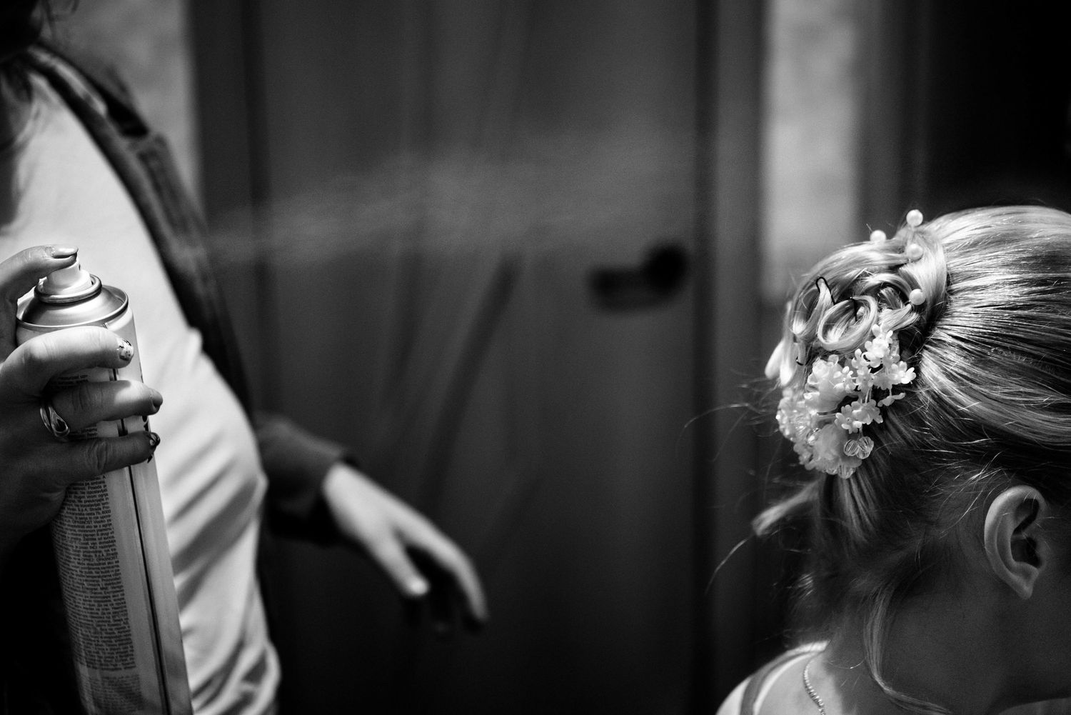 Black and white wedding photo showing an elegant updo with floral hair accessories in soft focus.