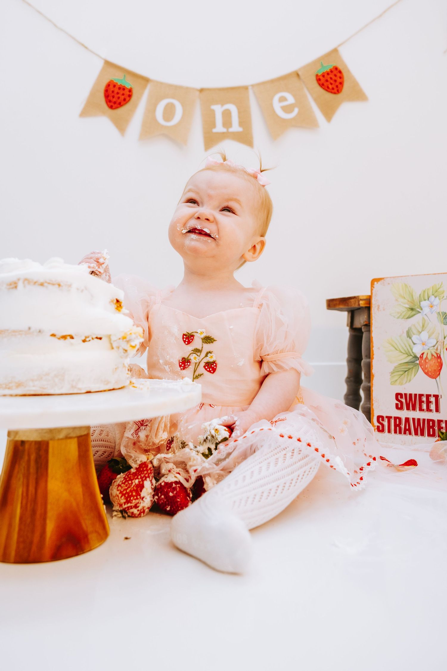 A birthday celebration with white cake and strawberry banner decorations.